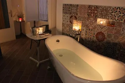 a bathroom with a tub and a table with candles at Dimore de La Rosa in Palermo