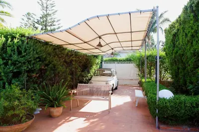 a patio with an umbrella and a car under it at Siciliaiu in Mondello