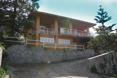 a house over a stone wall with a stone fence at Lomarchi Holiday Home in Carini