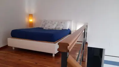a bedroom with a bed with blue sheets and a staircase at Casa Ranieri Palermo in Palermo