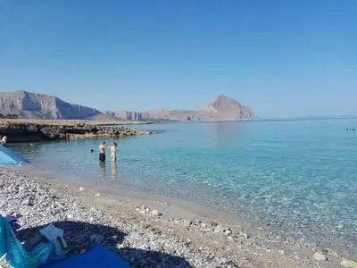 two people standing in the water on a beach at Karma B&B in San Vito lo Capo