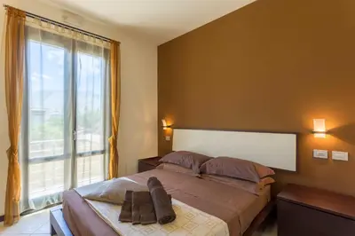 a bedroom with a bed and a large window at Karma B&B in San Vito lo Capo