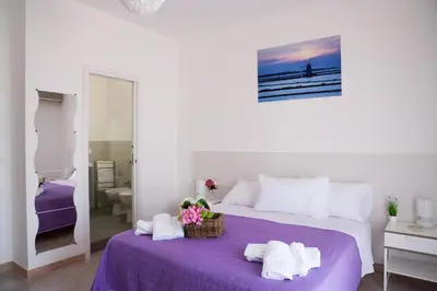 a white bedroom with a purple bed with towels on it at Sui tetti b&b in Alcamo