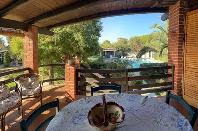a table on a porch with a view of a pool at Villa lo Iacono in Terrasini