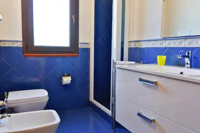 a blue bathroom with a sink and a toilet at Verdemare in Cefalù