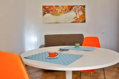 a white table with orange chairs and a coffee cup on it at Verdemare in Cefalù