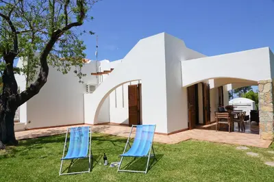 two chairs sitting on the grass in front of a house at Verdemare in Cefalù