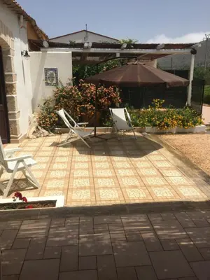 a patio with two chairs and an umbrella at Lovely Cottage in Castellammare del Golfo