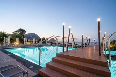 a swimming pool with a wooden walkway and stairs next to a building at Domina Zagarella Sicily in Santa Flavia