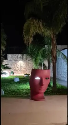a red pot sitting in front of a palm tree at Villa Ruffino in Balestrate
