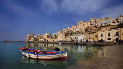 a boat sitting in the water next to a city at Case di Maria in Castellammare del Golfo