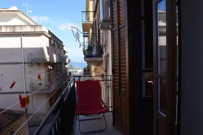 a red chair sitting on the balcony of a building at Chic Apartment Le Monde in Castellammare del Golfo