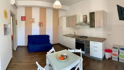 a small kitchen with a table and a blue chair at Appartamento Il Pomodoro in San Vito lo Capo