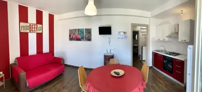 a living room with a red couch and a table at Appartamento Il Pomodoro in San Vito lo Capo