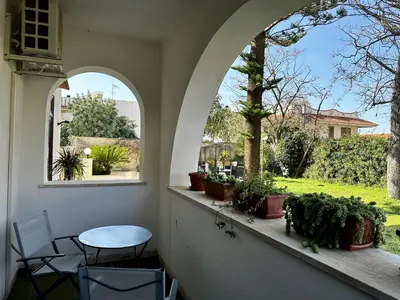a patio with an arched window and a table and chairs at Garden House Alla Torre in Isola delle Femmine