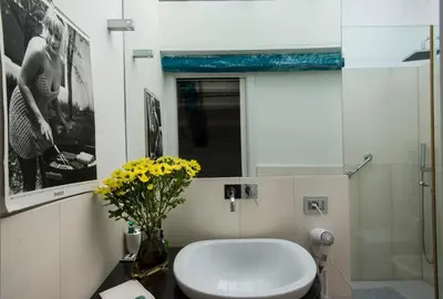a bathroom with a toilet and a vase of yellow flowers at Trikeles in Palermo