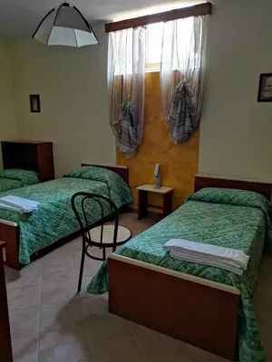a room with two beds and a table and a window at Albergo Ristorante Pizzeria Del Viale in Palazzo Adriano