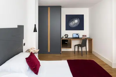 a bedroom with a bed and a desk with a chair at Hotel Plaza Opéra in Palermo