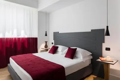 a bedroom with a large bed with red sheets at Hotel Plaza Opéra in Palermo