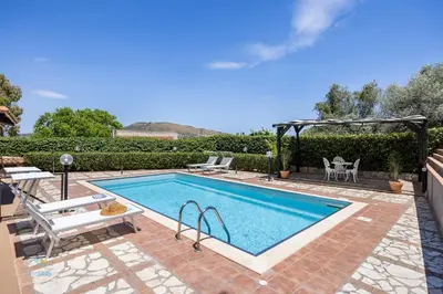 a swimming pool with two chairs and a gazebo at Villa Cocos in Casteldaccia