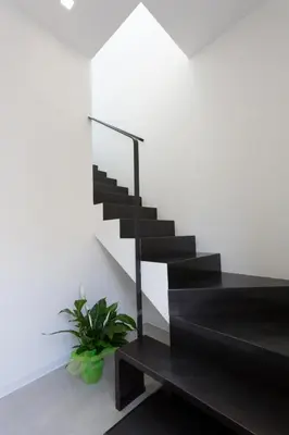 a black staircase in a white room with a plant at Catalina in San Vito lo Capo