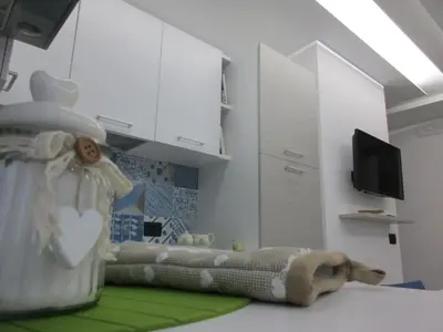 a kitchen with white cabinets and a green rug at Le Dimore di Enea in Castellammare del Golfo