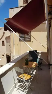 a balcony with a table and chairs on a building at La Perla Bianca in Castellammare del Golfo