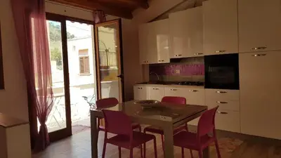 a kitchen with a table and chairs and a kitchen with a door at La Perla Bianca in Castellammare del Golfo