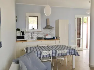 a kitchen with a table and chairs in a room at Un mare di Blu - Casa Cobalto in Macari