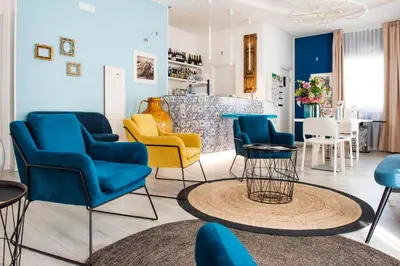 a living room with blue and yellow chairs and a table at Marina di Petrolo Hotel & SPA in Castellammare del Golfo