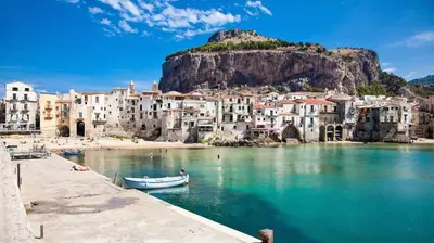 a group of buildings on a beach with a boat in the water at Arvilla's Houses in Campofelice di Roccella