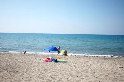 a group of people on a beach with an umbrella at Arvilla's Houses in Campofelice di Roccella