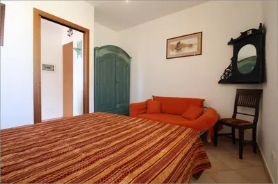 a bedroom with a bed and a chair and a mirror at Senia in San Vito lo Capo