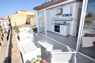 a balcony with white furniture and a kitchen at Terrazza in Palazzo Taormina in Castellammare del Golfo