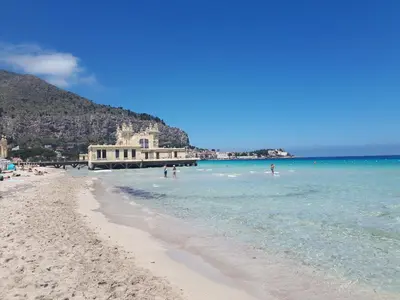 a beach with people swimming in the water at B&B Mondello Design in Mondello