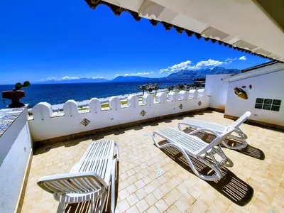 a balcony with chairs and the ocean in the background at Seafront House Gabbiano Azzurro in Santa Flavia