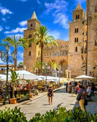 a woman walking through a plaza in front of a building at Seafront House Gabbiano Azzurro in Santa Flavia