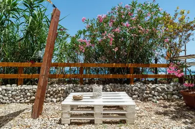 a table in front of a fence with pink flowers at Dimore di mare - Beachfront Apartments in Santa Flavia