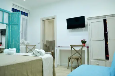 a bedroom with two beds and a desk and a tv at Piazza Marina in Palermo