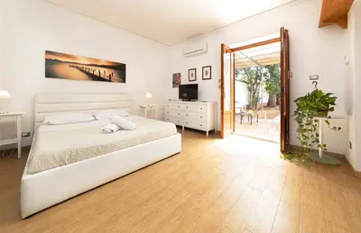 a white bedroom with a bed and a sliding glass door at Maison Blanche in Palermo