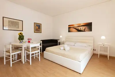 a white bedroom with a bed and a table at Maison Blanche in Palermo