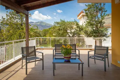 a porch with three chairs and a table with a vase of flowers at Maison Blanche in Palermo