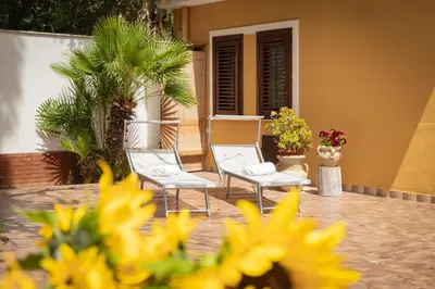 two white chairs sitting on a patio with flowers at Maison Blanche in Palermo