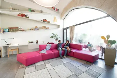 two women sitting on a pink couch in a living room at Gattopardo Apartments - LAGO Design by Wonderful Italy in Palermo