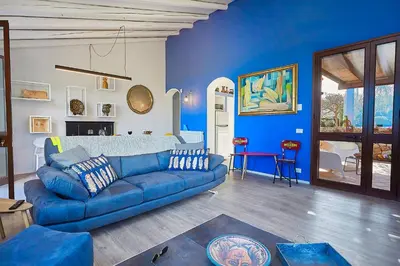 a living room with a blue couch and a blue wall at Villa Tarì in Scopello