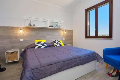 a bedroom with a purple bed and a blue chair at Villa Tarì in Scopello