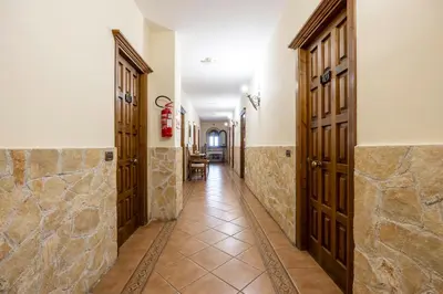 a hallway with wooden doors and tile floors at Hotel Castello di Giuliano in Montelepre