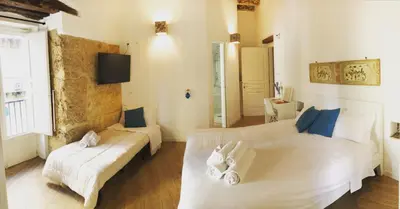 a bedroom with two white beds and a couch at Bedda Mari Rooms & Suite in Palermo