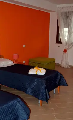 a bedroom with two beds and an orange wall at B&B Federico II in San Cipirello