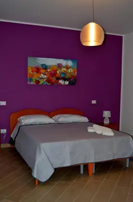 a bedroom with a bed with a purple wall at B&B Federico II in San Cipirello